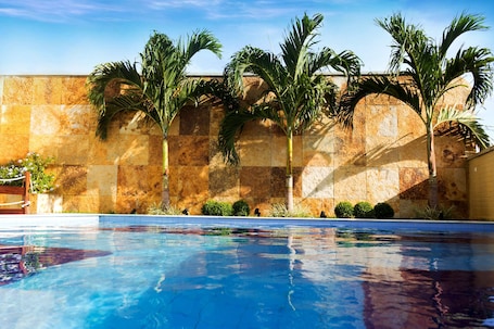 Una piscina al aire libre, sombrillas, sillones reclinables de piscina