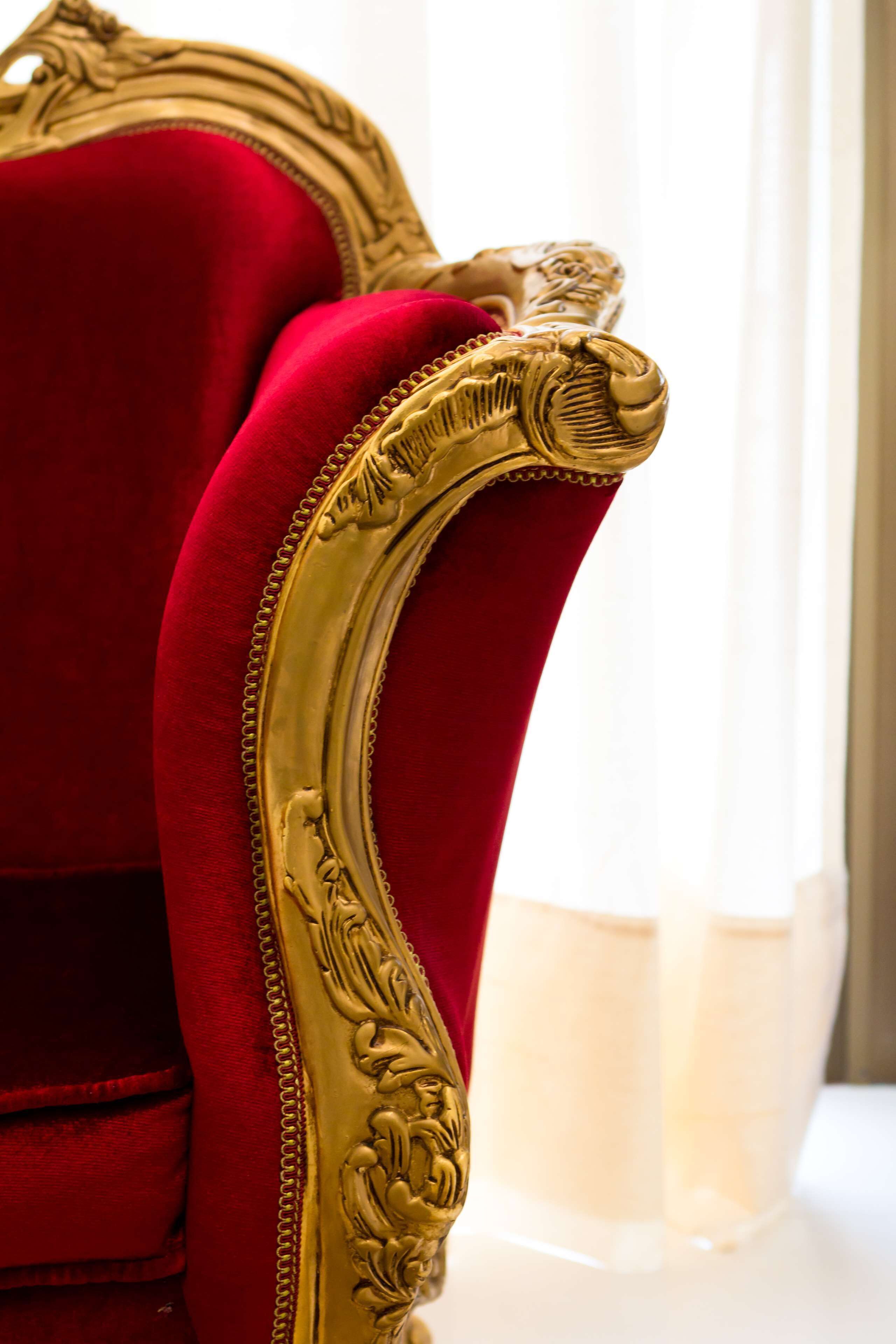 Primer plano de una butaca de terciopelo rojo con detalles dorados ornamentales.