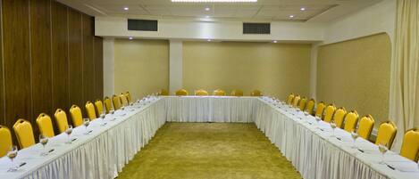 A conference room with a long table, yellow chairs, and a chandelier.