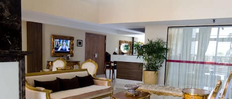 A luxurious living room with a sofa, armchairs, a coffee table, and a television.
