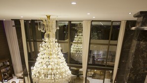 Eine geräumige Lobby mit einem großen Chandelier, einem runden Tisch mit Stühlen und einem Sofa.