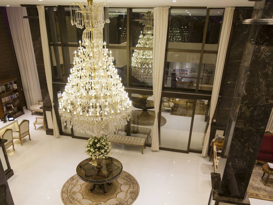Eine geräumige Lobby mit einem großen Chandelier, einem runden Tisch mit Stühlen und einem Sofa.