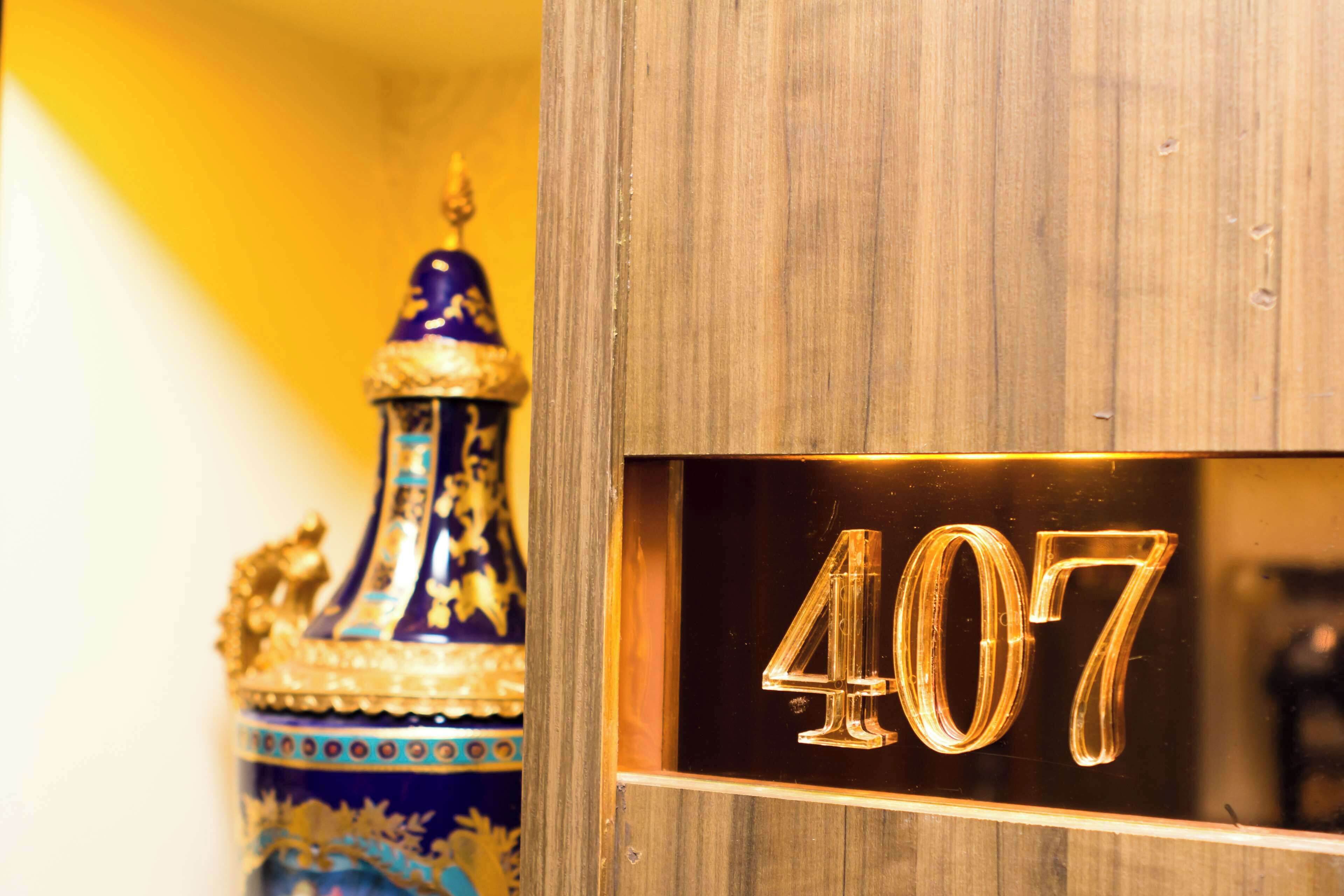 Una puerta de madera con el número 407 y un jarrón azul y dorado decorativo.