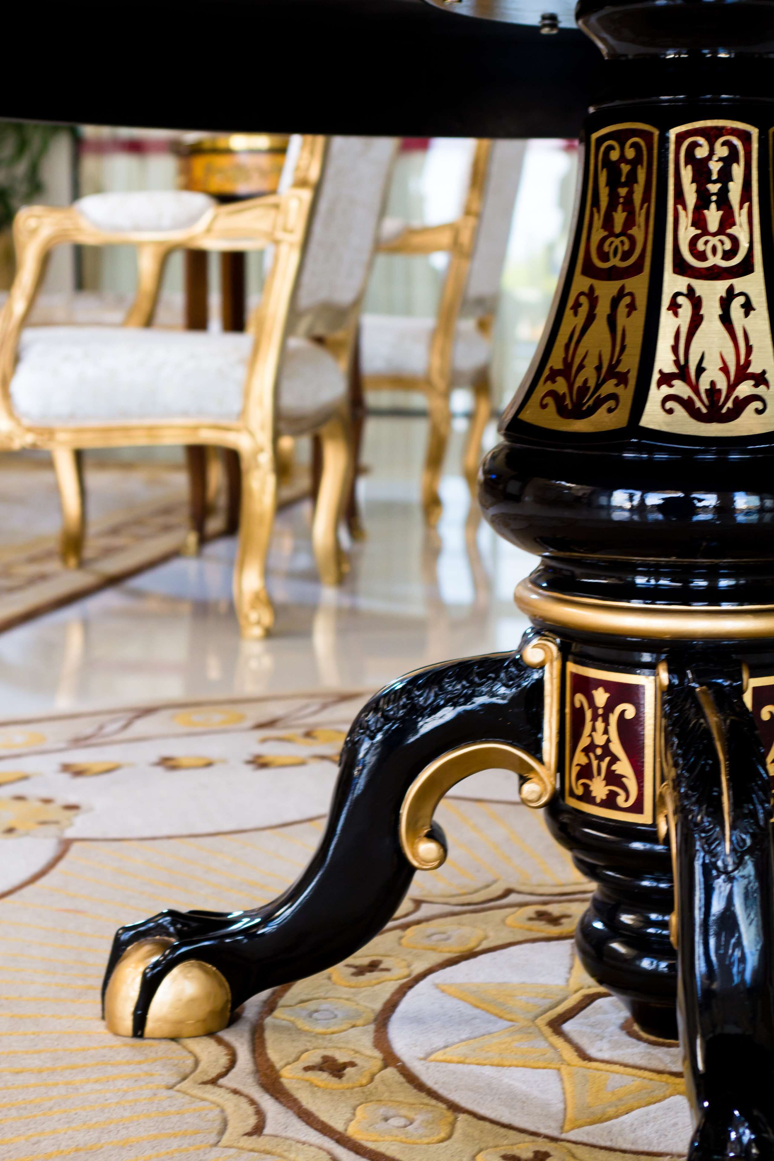 A close-up of a black and gold ornate table leg with a gold knob.