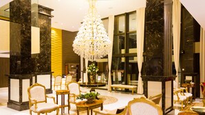 Eine luxuriöse Lobby mit Marmorsäulen, edlen Kronleuchtern und klassischen Möbeln.