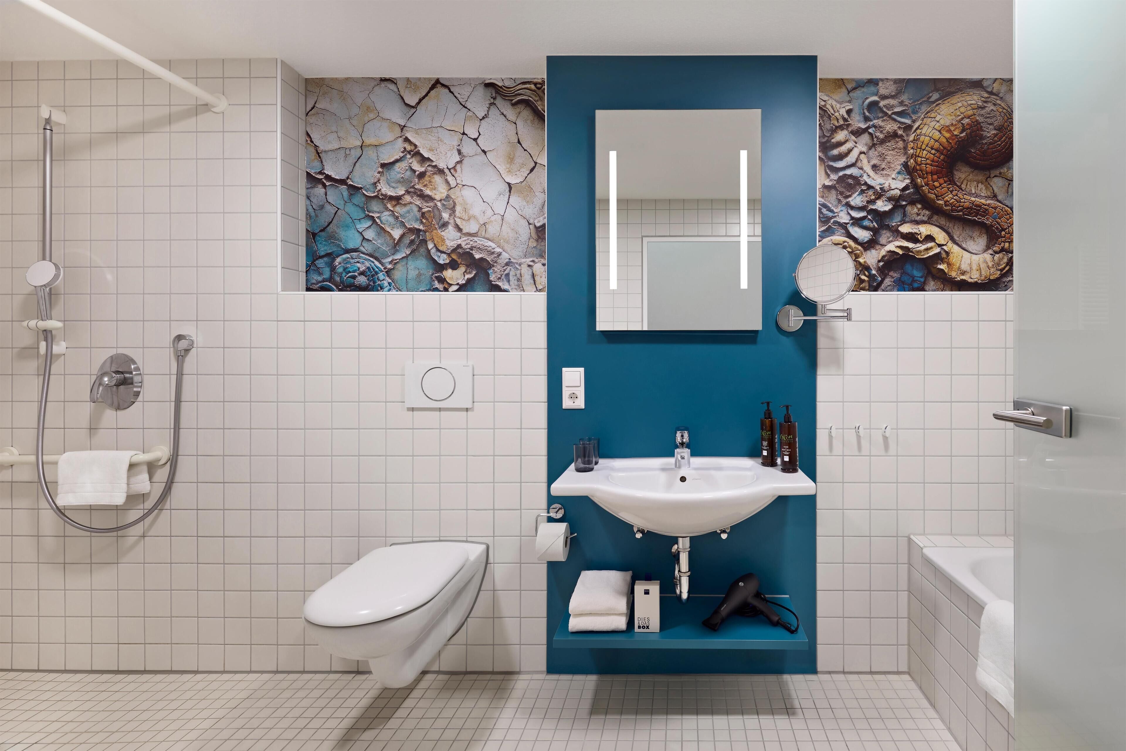 Un baño moderno con inodoro blanco, ducha, lavabo con espejo y pared de acento azul.
