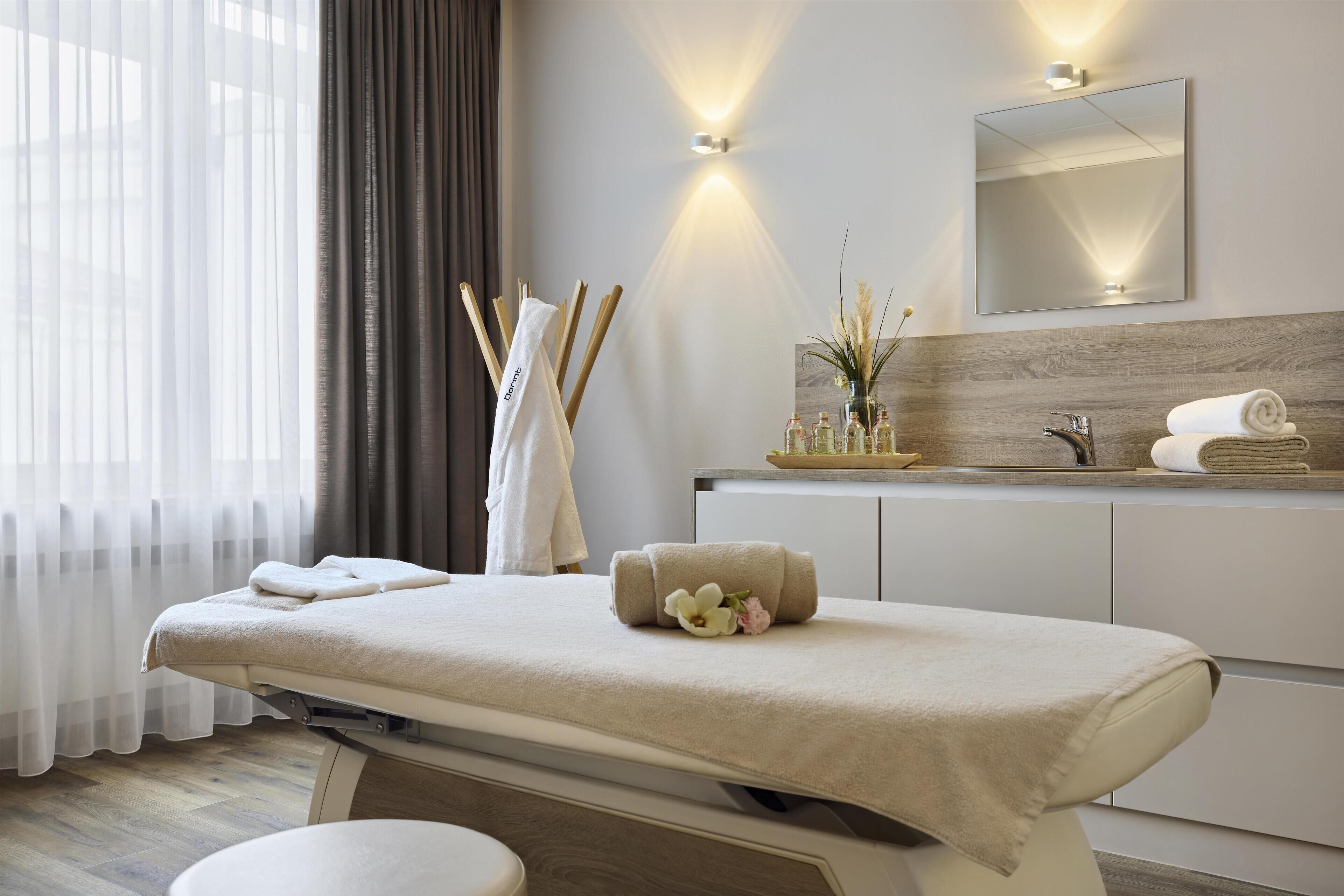 Un moderno spa con camilla de masaje, espejo y tocador con toallas y artículos de aseo.