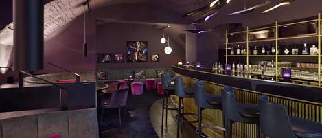 Eine Bar mit einer gebogenen Theke, Barhocker und Regalen mit Flaschen.