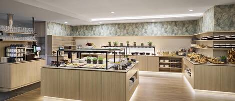 Un área de cocina moderna con armarios de madera, una isla central con encimera de vidrio y varios electrodomésticos.