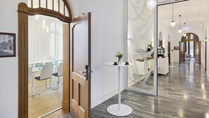 A modern hotel lobby with a wooden door, a round white table with a vase, and a glass partition reflecting the interior. - Dorint Parkhotel Jordanbad Biberach an der Riß (Biberach an der Riss)