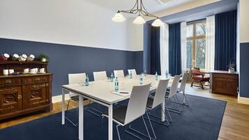 A conference room with a white table, chairs, and a wooden cabinet with dishes.