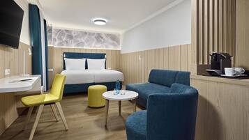 Een moderne hotelkamer met een bed, een bureau, een stoel, een bank en een klein rond tafeltje.
