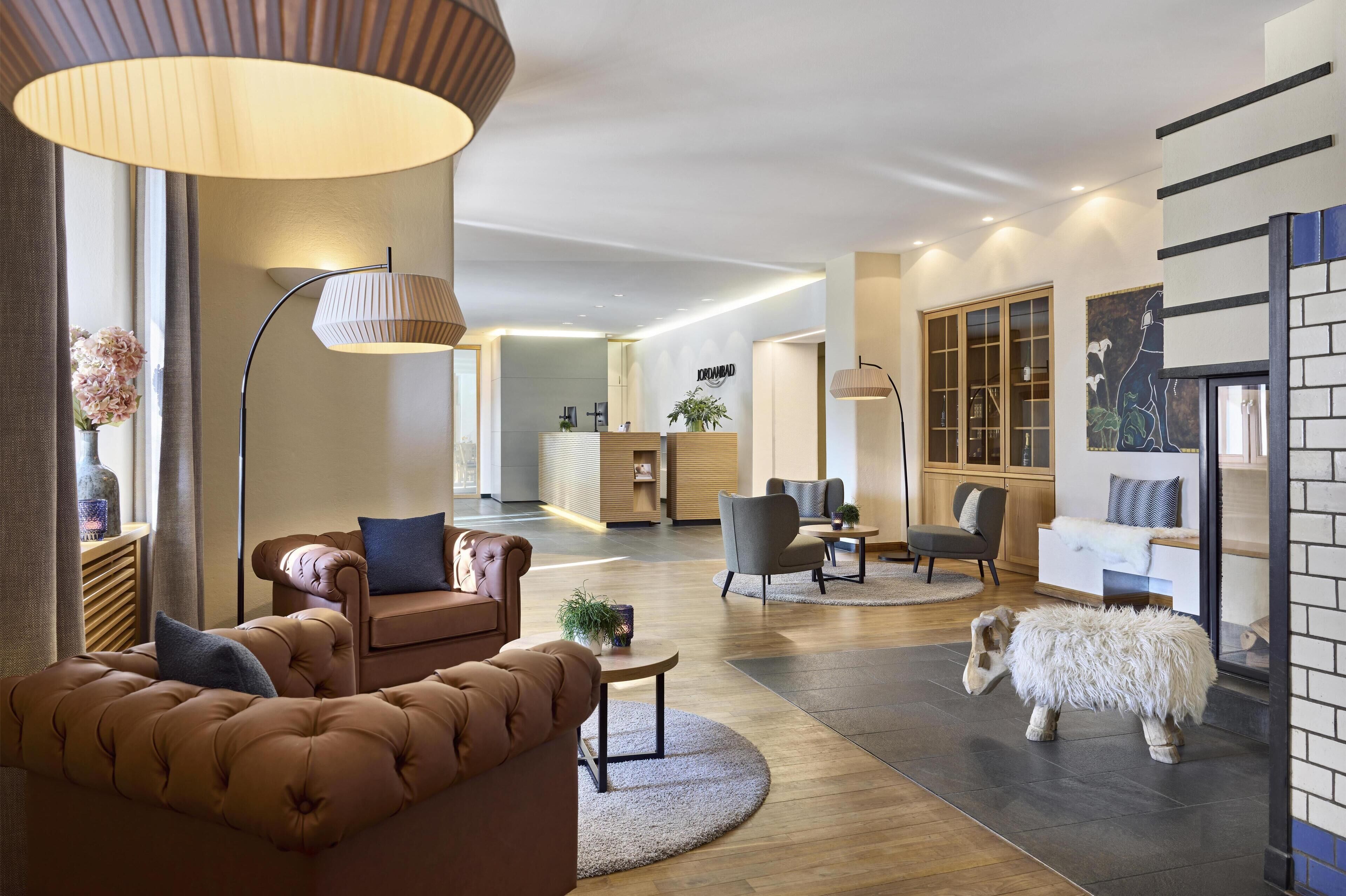 A modern hotel lobby with a plush sofa, a round table, and a unique sheep sculpture.