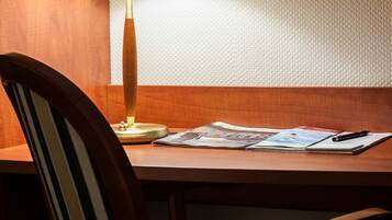 A wooden chair with a striped cushion, a table with a lamp, and a magazine.