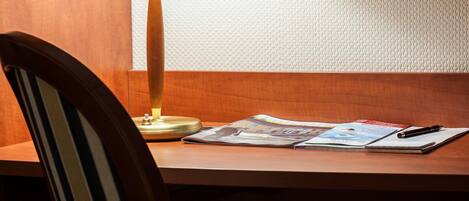 A wooden chair with a striped cushion, a table with a lamp, and a magazine.