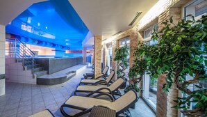 A spa area with sun loungers, a staircase, and a view of the pool area.