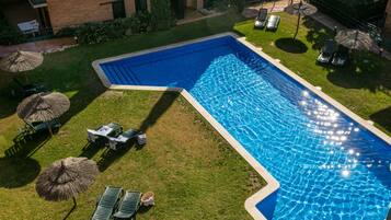 A rectangular swimming pool with a clear blue water surface, surrounded by a well-maintained lawn and several lounge chairs.