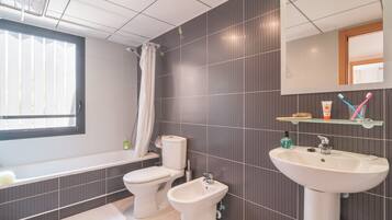 Un baño moderno con bañera, inodoro, bidé y lavabo.