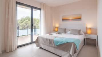 Een slaapkamer met een groot bed, uitzicht op een balkon en een schilderij aan de muur.