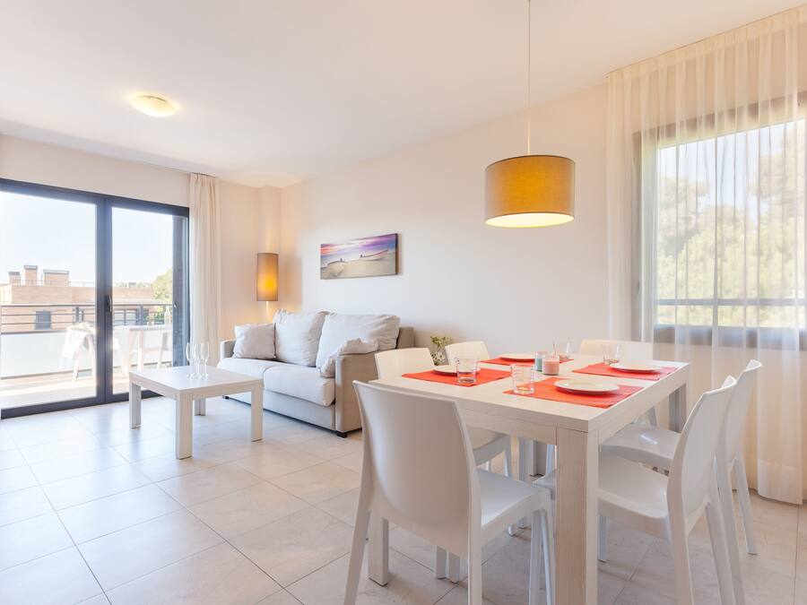Una sala de estar moderna con comedor, que incluye un sofá, una mesa de comedor con sillas, una lámpara colgante y un ventanal con cortinas.