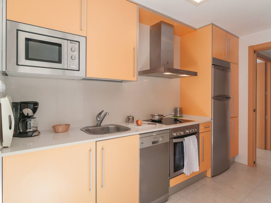Una cocina moderna con microondas, cafetera, fregadero y electrodomésticos de acero inoxidable.