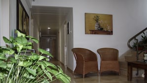 A hallway with two wicker chairs, a potted plant, and a painting on the wall. - Ga'aton Motel (Nahariya)