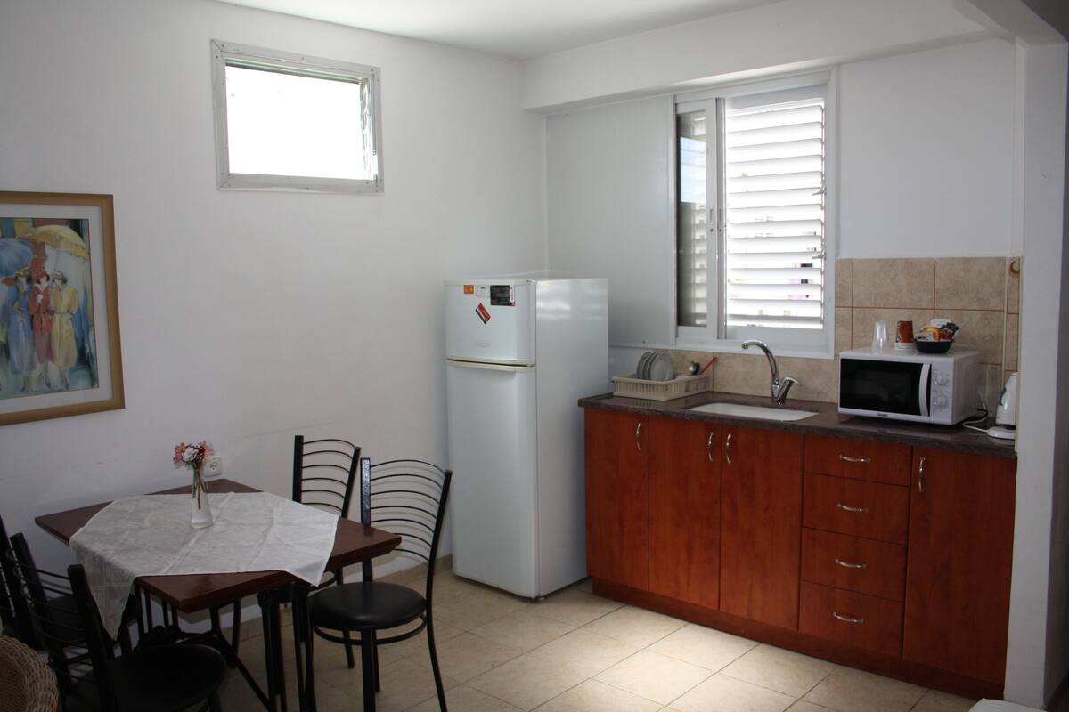 A compact kitchen with a refrigerator, microwave, sink, and wooden cabinets.