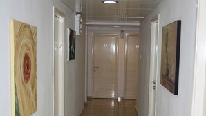 A hallway with a tiled floor, white walls, and doors numbered 13 to 14. - Ga'aton Motel (Nahariya)