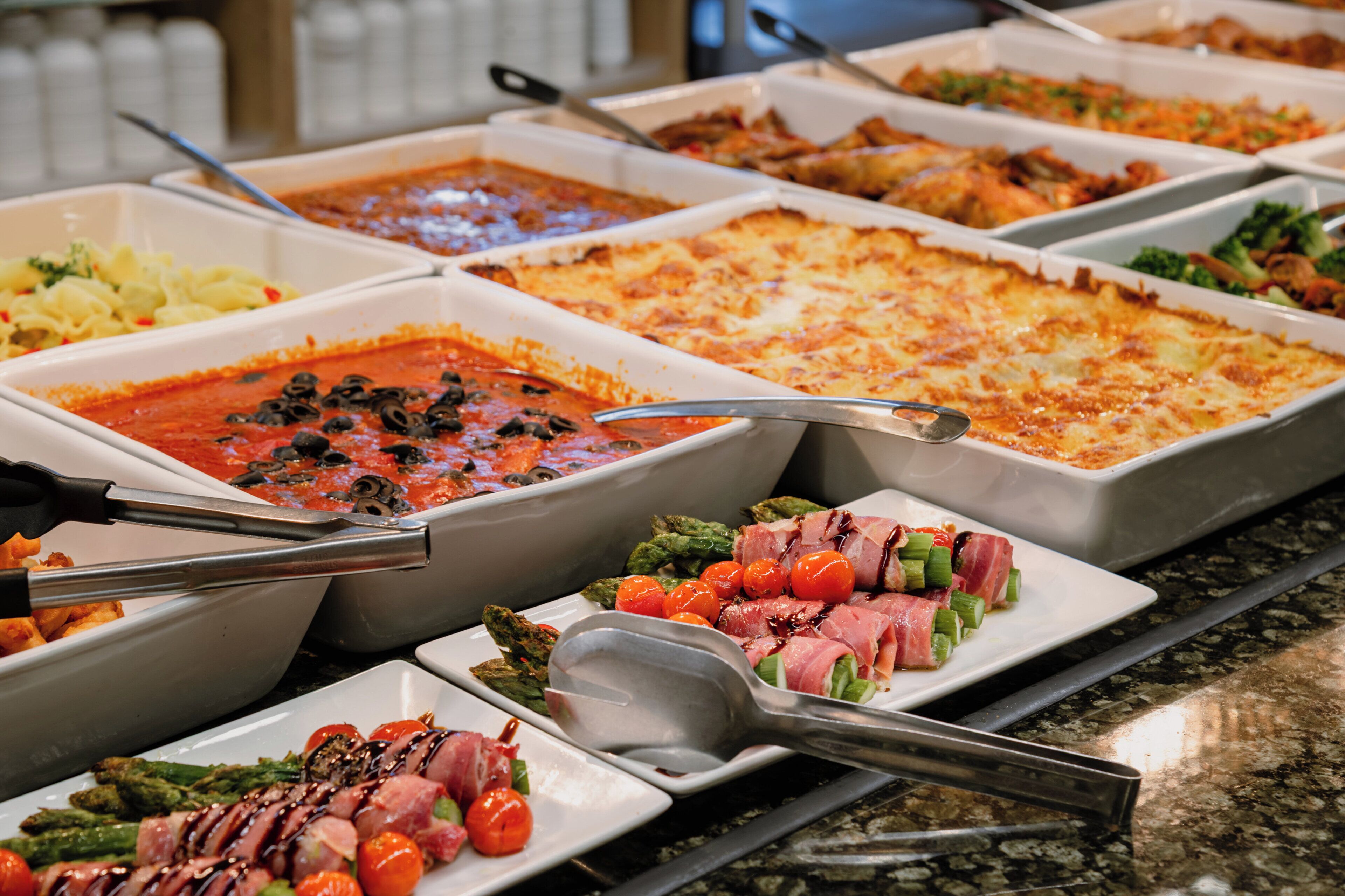 Un bufé con diversos platos, como pasta, ensaladas y carnes.