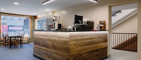 Eine moderne Bar mit Holztresen, einer Kaffeemaschine und einer Sitzecke mit Stühlen.