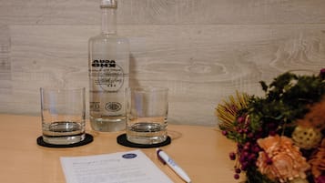 Una mesa de madera con una botella, dos vasos, un bolígrafo y un documento.