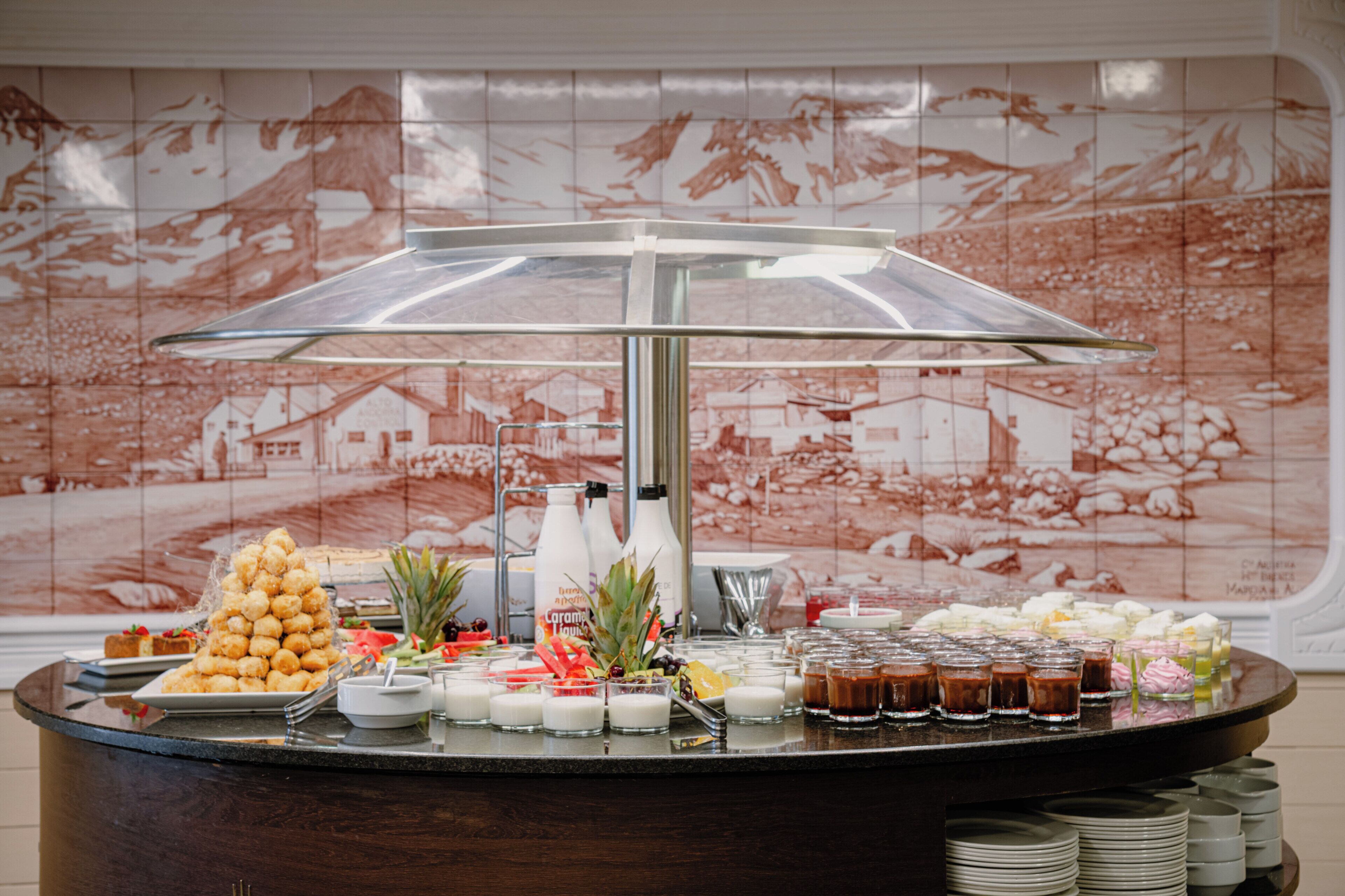 Un bufé con una variedad de alimentos y bebidas, que incluye una pirámide de pasteles, frutas y una selección de refrescos.