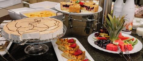 A buffet table with various food items including a cake, fruit, and sandwiches.