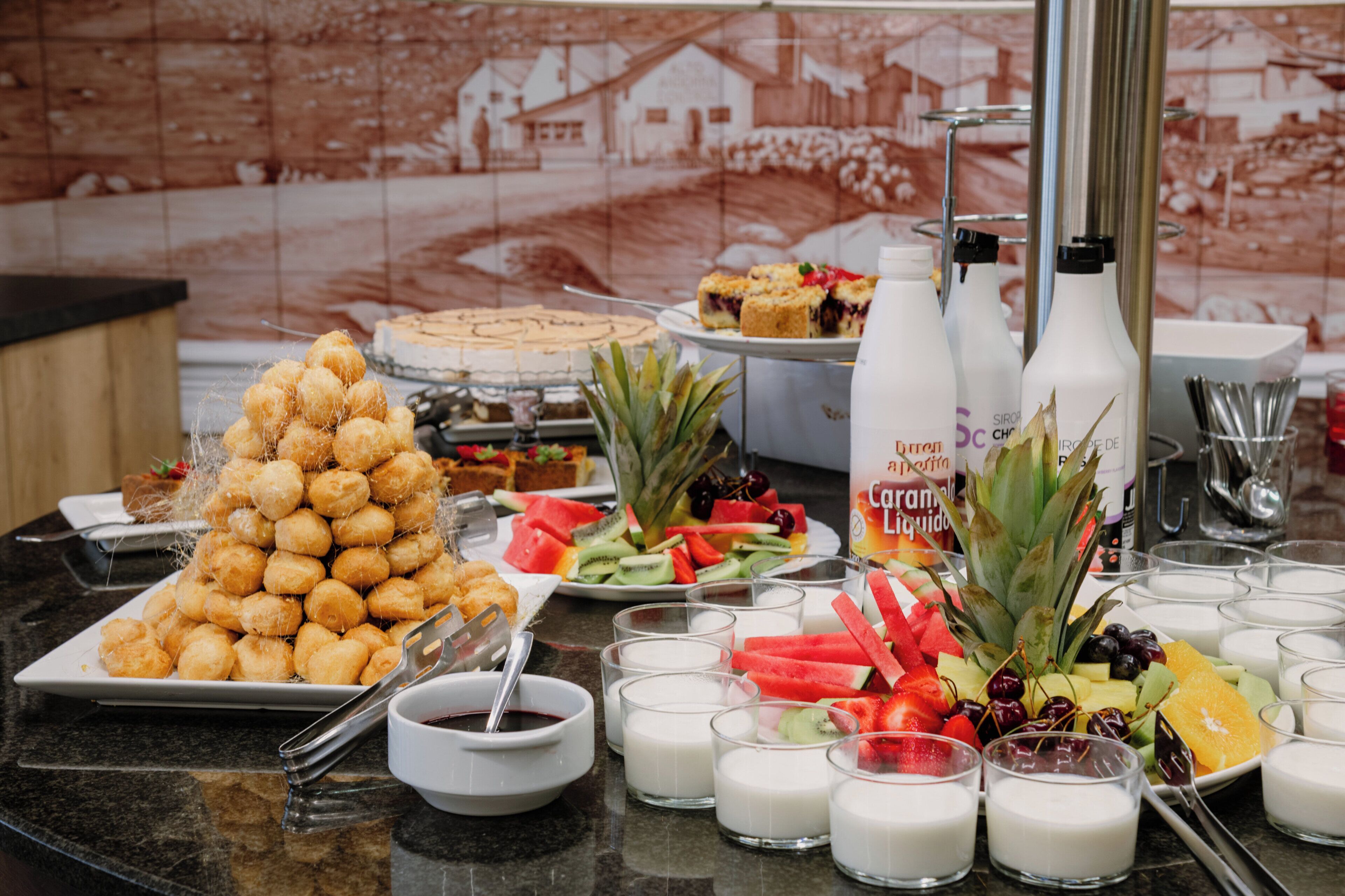 A buffet table with various food items, including a pyramid of doughnuts, fruit, and dairy products.