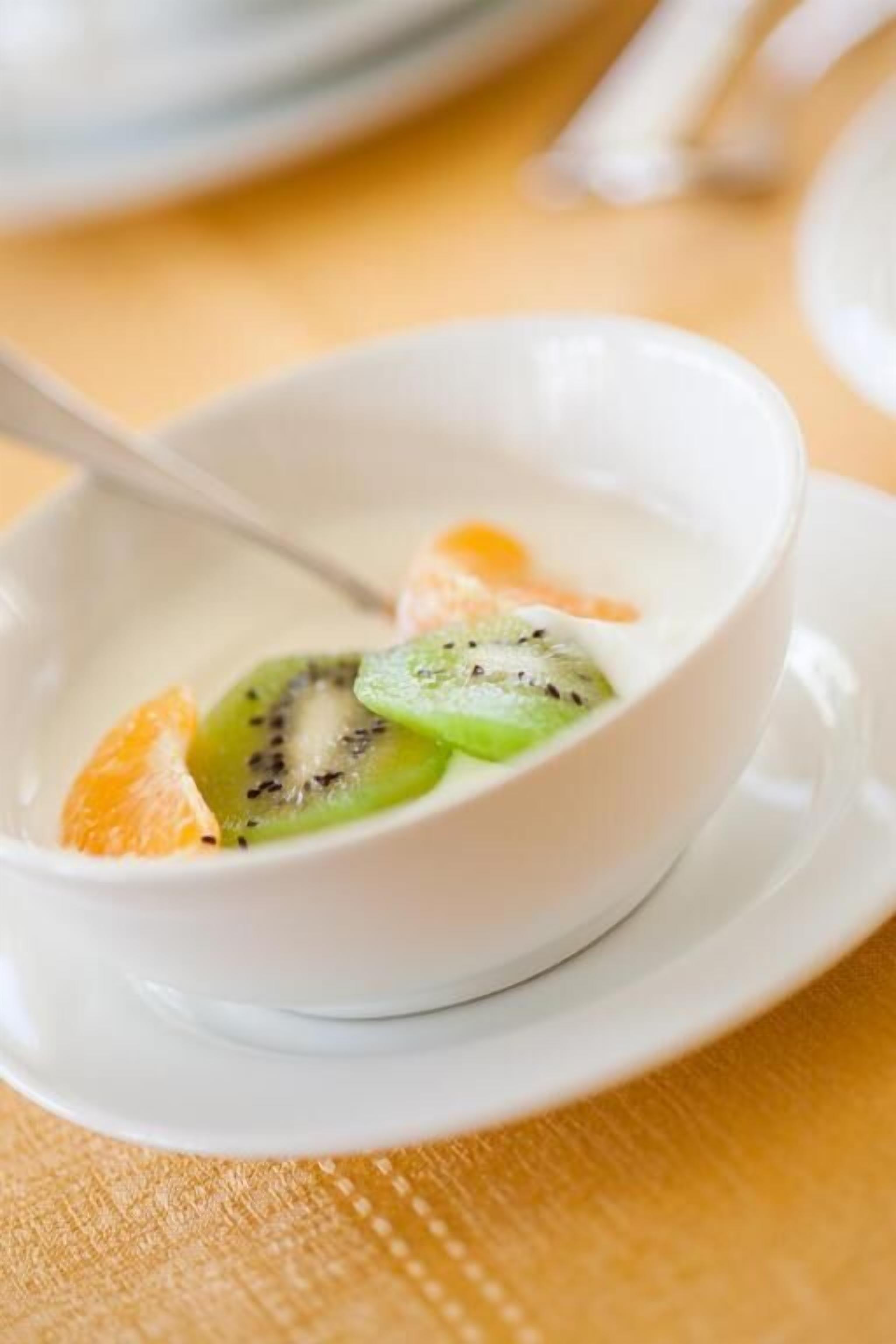 A bowl of dessert with fruit on a white plate.