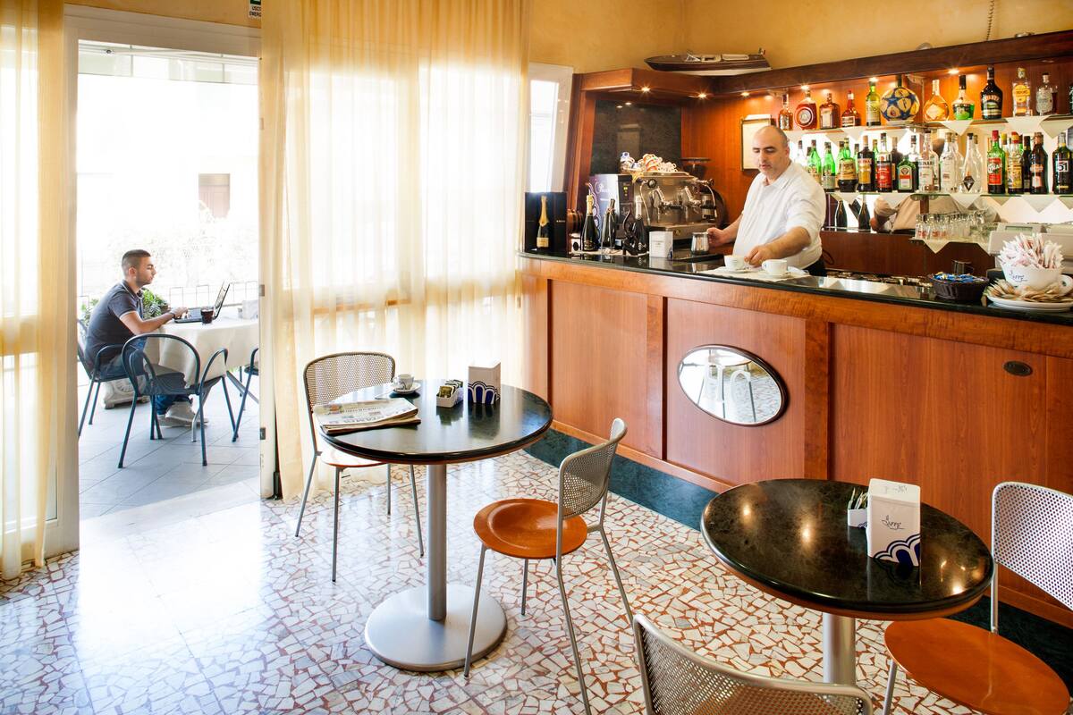 Een bar met een toonbank, stoelen en een betegelde vloer.
