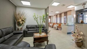 Un área de espera moderna con sofás de cuero, una mesa de centro de madera y plantas decorativas.