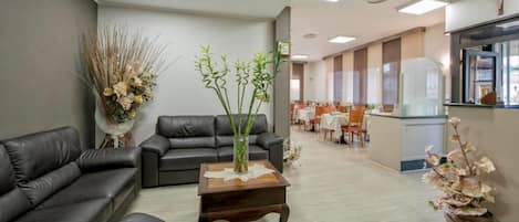 Un área de espera moderna con sofás de cuero, una mesa de centro de madera y plantas decorativas.