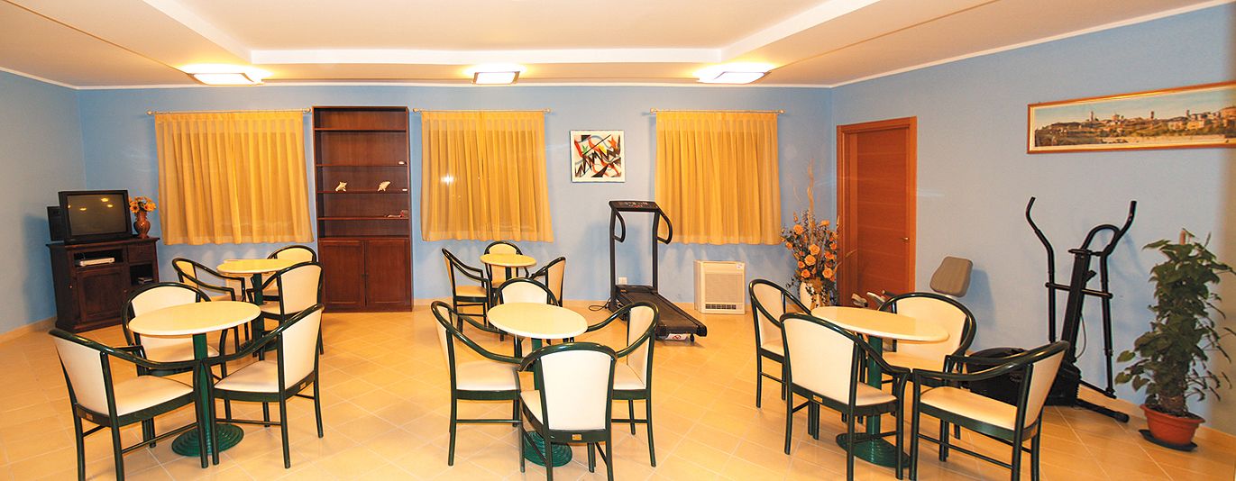 Una habitación con zona de comedor, equipo de ejercicio y televisor.