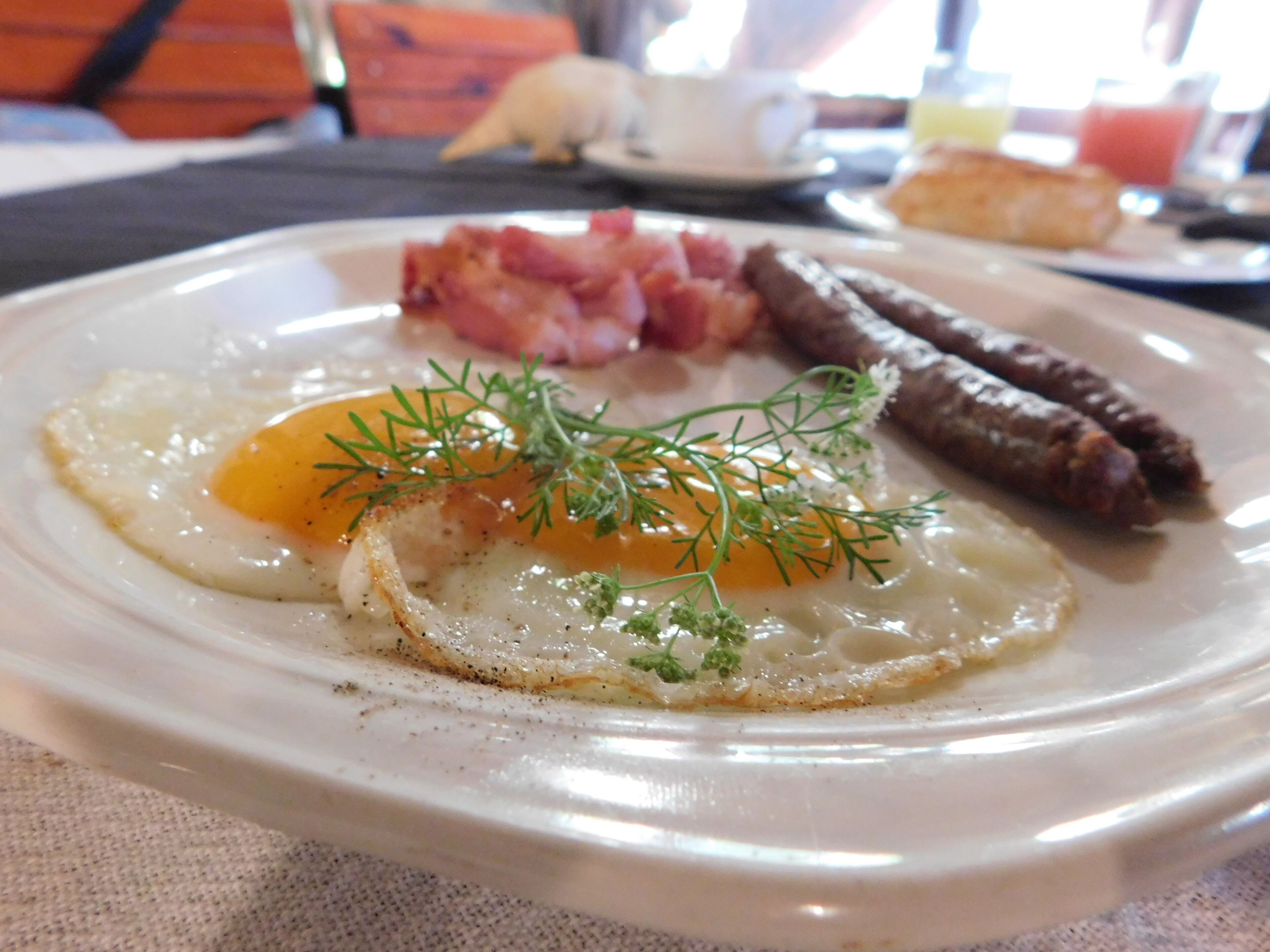 A breakfast plate with eggs, bacon, and sausages.