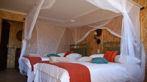 A room with two beds, each with white bedding and red throw blankets.