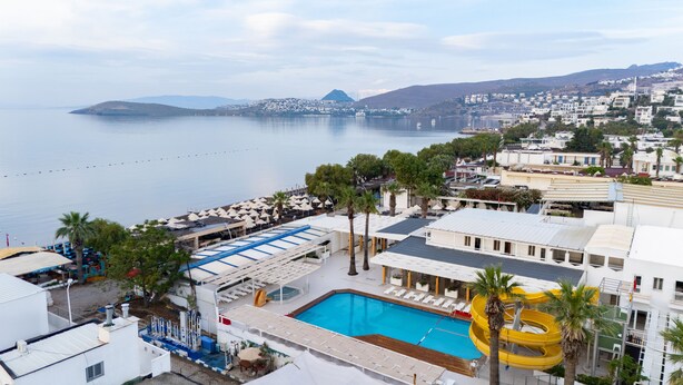 A hotel with a pool, sun loungers, and a view of the sea. - Petunya Beach Resort - All Inclusive (Bodrum)