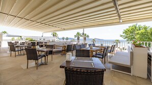 An outdoor dining area with tables and chairs, a covered seating area, and a view of the sea. - Petunya Beach Resort - All Inclusive (Bodrum)