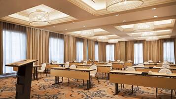 Un salón de conferencias con varias mesas, sillas y un atril.
