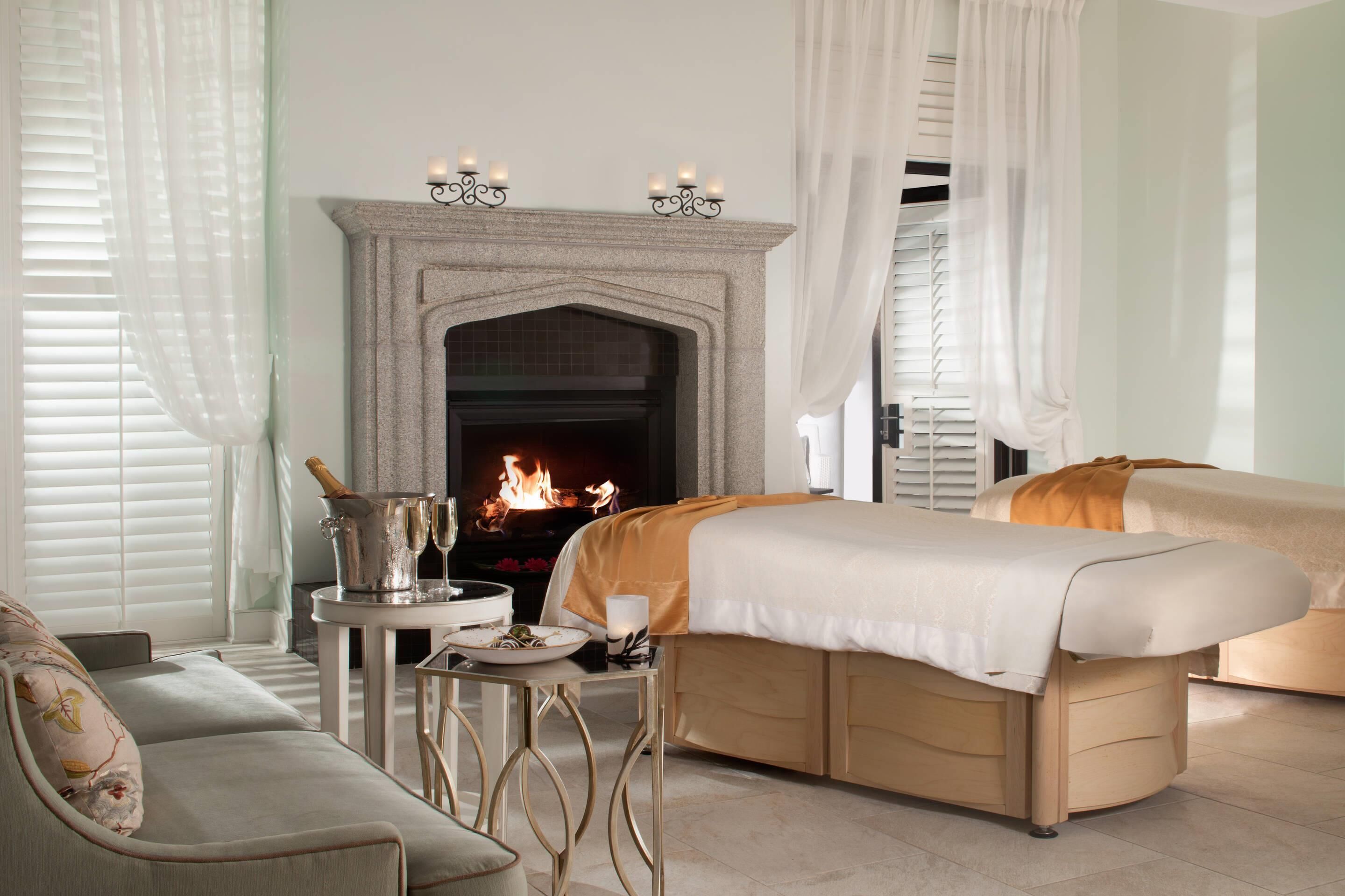A hotel room with a fireplace, a bed, a sofa, and a small table with a candle.