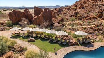 Una piscina al aire libre, sombrillas, sillones reclinables de piscina