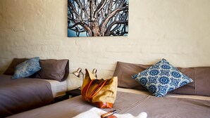 A hotel room with two beds, a large painting on the wall, and a bag on the floor. - Solitaire Lodge (Solitaire)