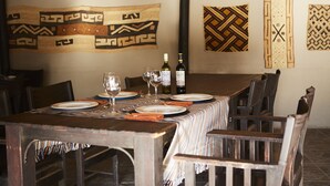 A dining area with a wooden table set for four, surrounded by chairs. There are wine glasses and bottles on the table. - Solitaire Lodge (Solitaire)