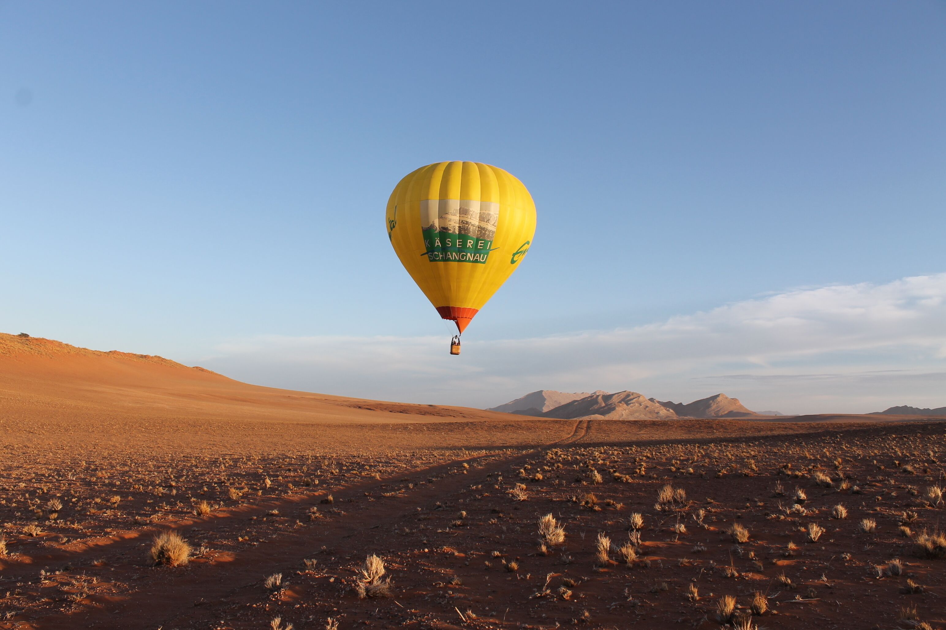 A hot air balloon in a desert landscape with mountains in the background.