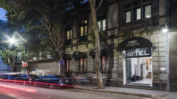 Un hotel de estilo arquitectónico clásico, con una entrada destacada que incluye un toldo negro y un cartel que dice